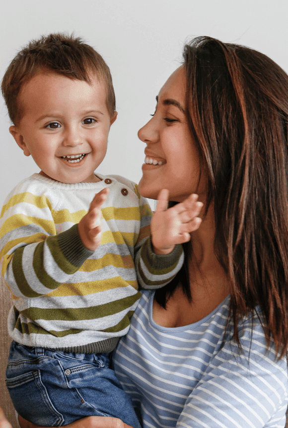 A happy mother smiling at her child who is clapping in joy