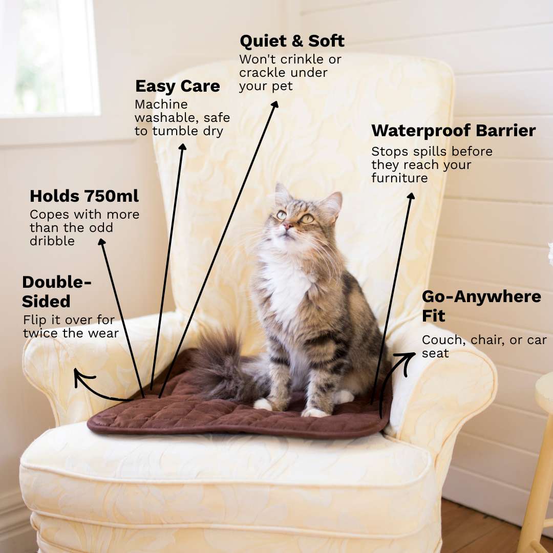 A fluffy gray tabby cat sits on a quilted brown pet cooling mat placed on an upholstered armchair. The image includes multiple callout text labels pointing to product features such as quiet and soft comfort, easy care, waterproof barrier, and go-anywhere fit.