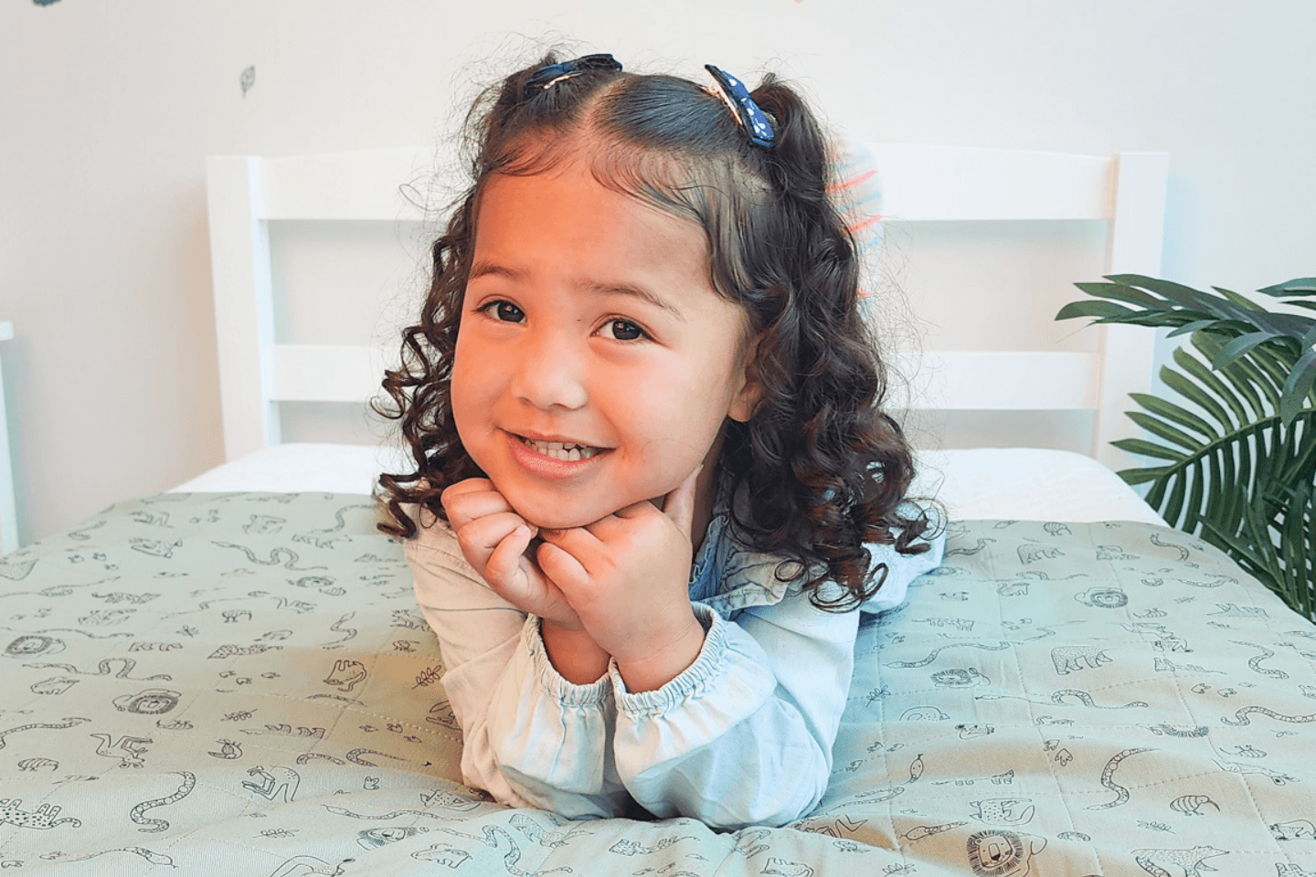 Smiling toddler on bed with our Brolly Sheets with Wings Animal Kingdom