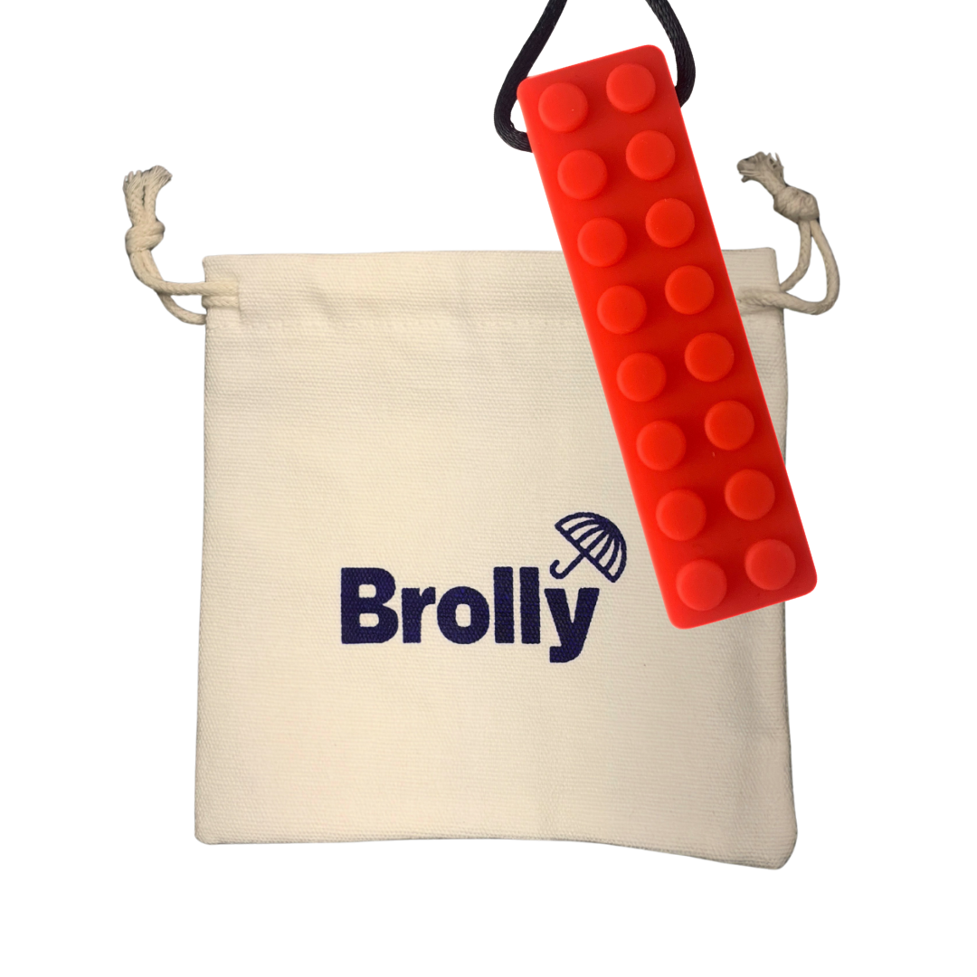 Beige drawstring pouch and brick-shaped Brolly Sheet Chew Necklace on a black cord against a white background - Red