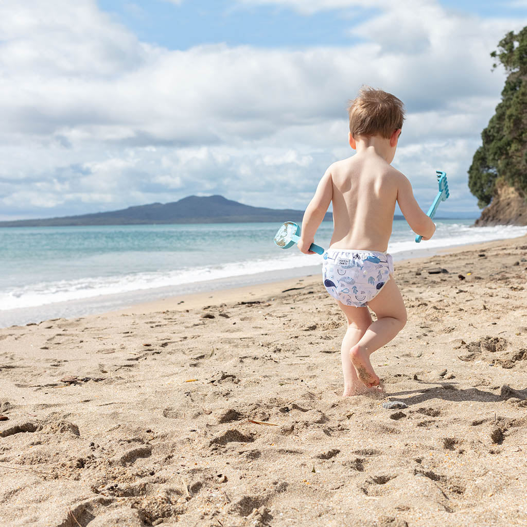 Child running on a sandy beach with mountains and ocean in the background  - Narwhales