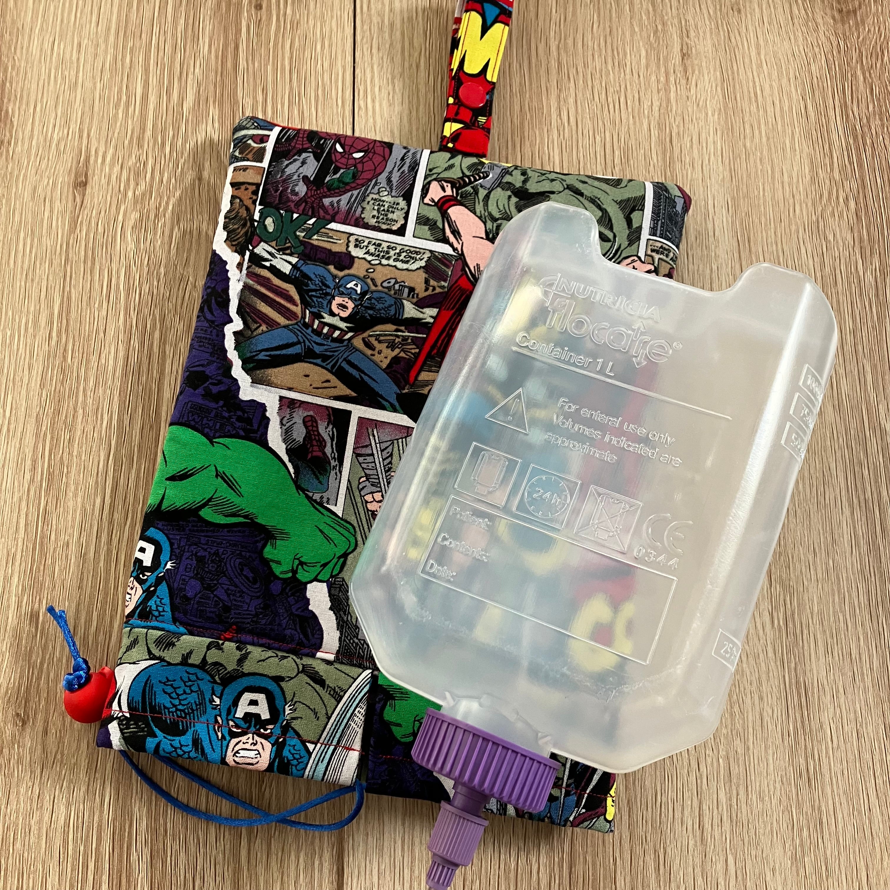 Superhero-themed bottle cover with a clear bottle on a wooden surface